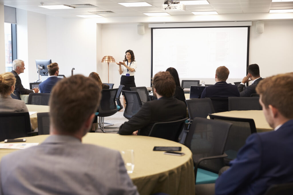 Business conference with speaker presenting to a group of professionals