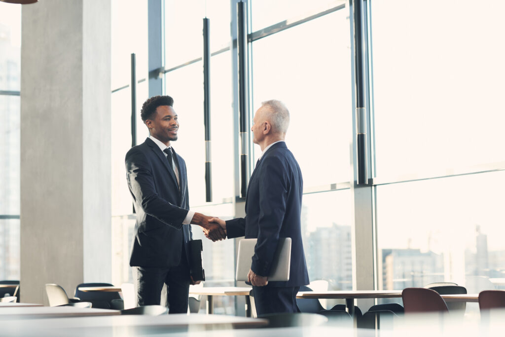 Two businessmen shaking hands in a modern office building